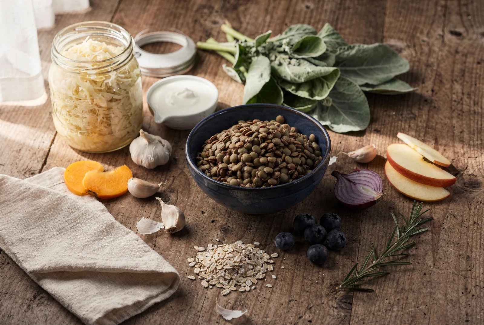 Sauerkraut, kefir, leafy greens, lentils, garlic, blueberries and oats on a wooden table