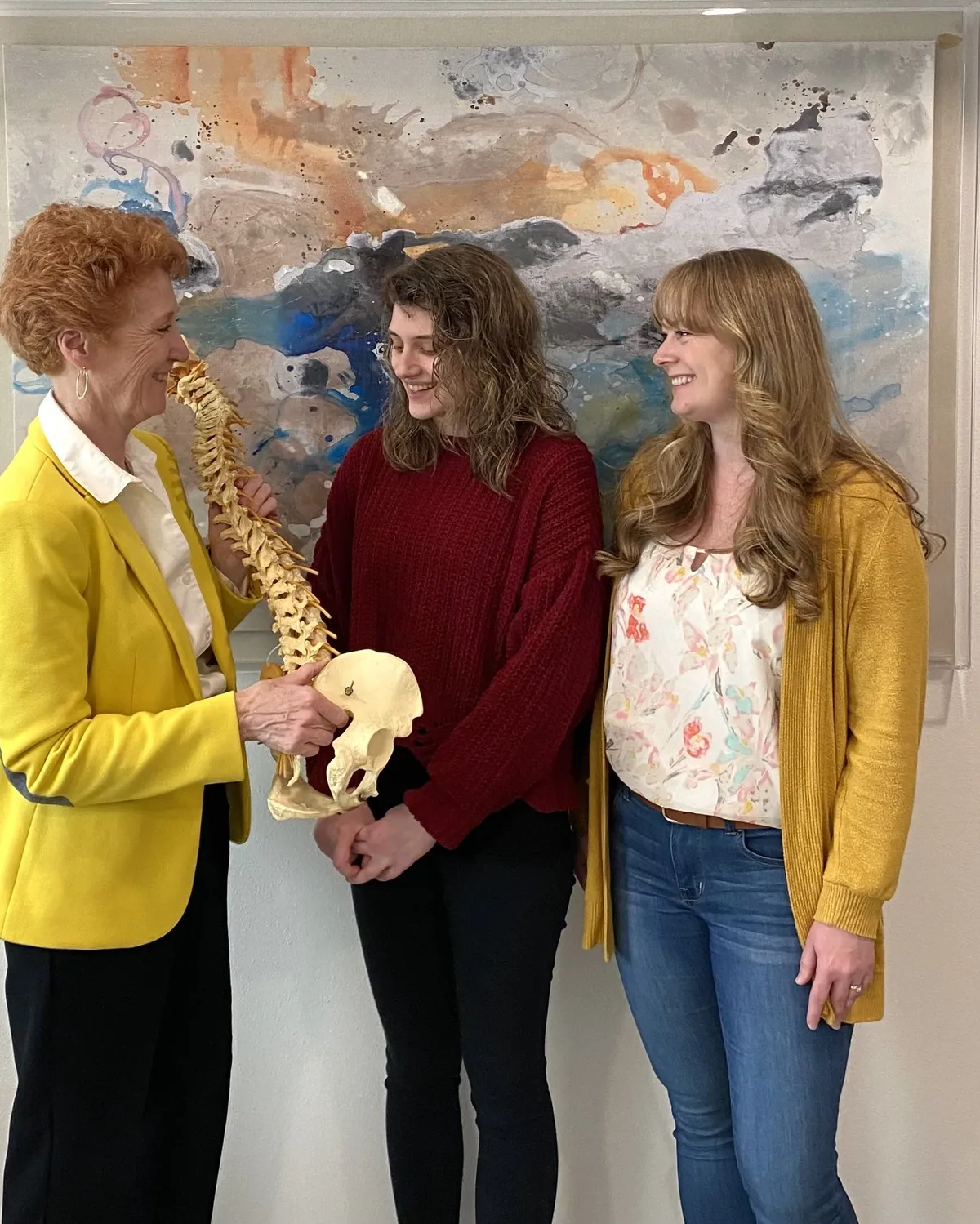 Dr. Mary Schmidt explaining a spine model to two patients in the Olympia office
